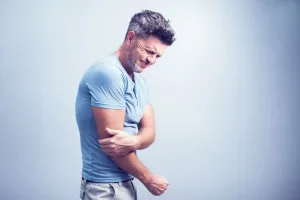 A man gripping his elbow in pain