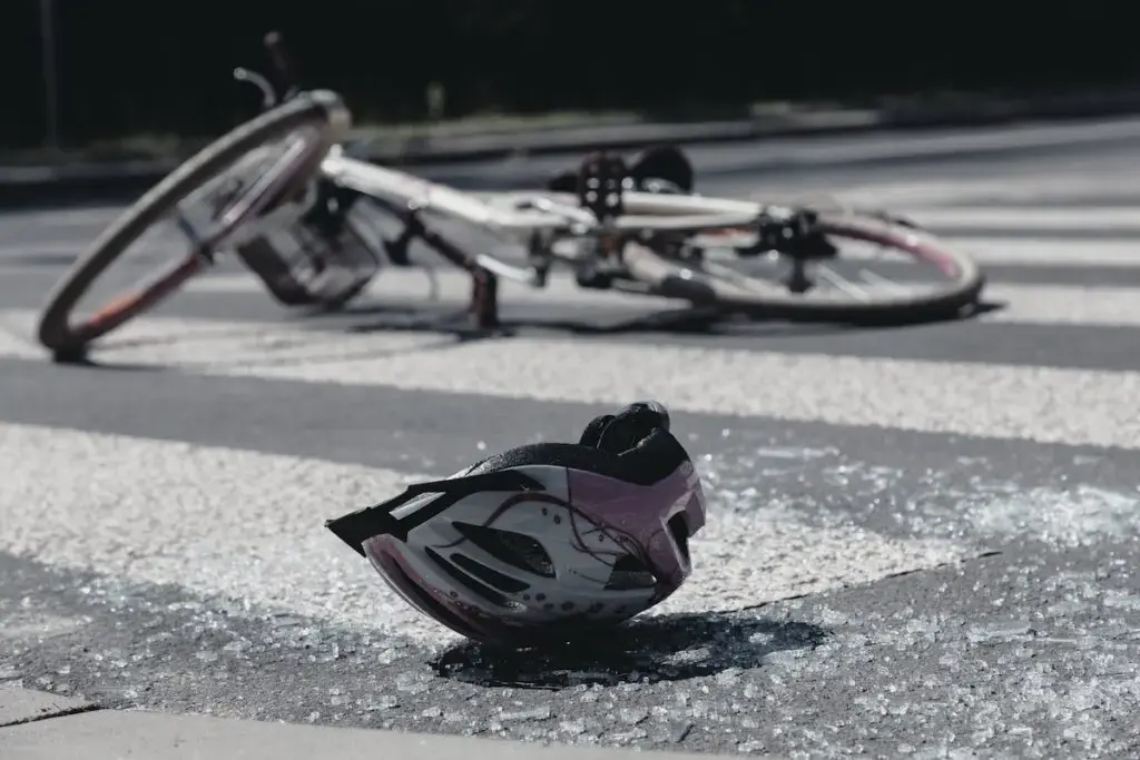 A bicycle and helmet lying in the street surrounded by broken glass