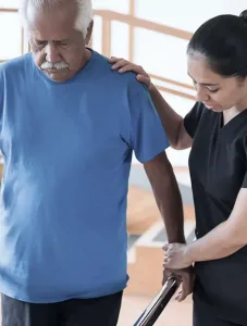 A physical therapist supporting a man as he walks