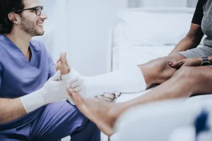 A doctor examining a patient wearing a cast on his ankle
