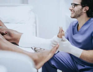 A doctor examining a patient wearing a cast on his ankle